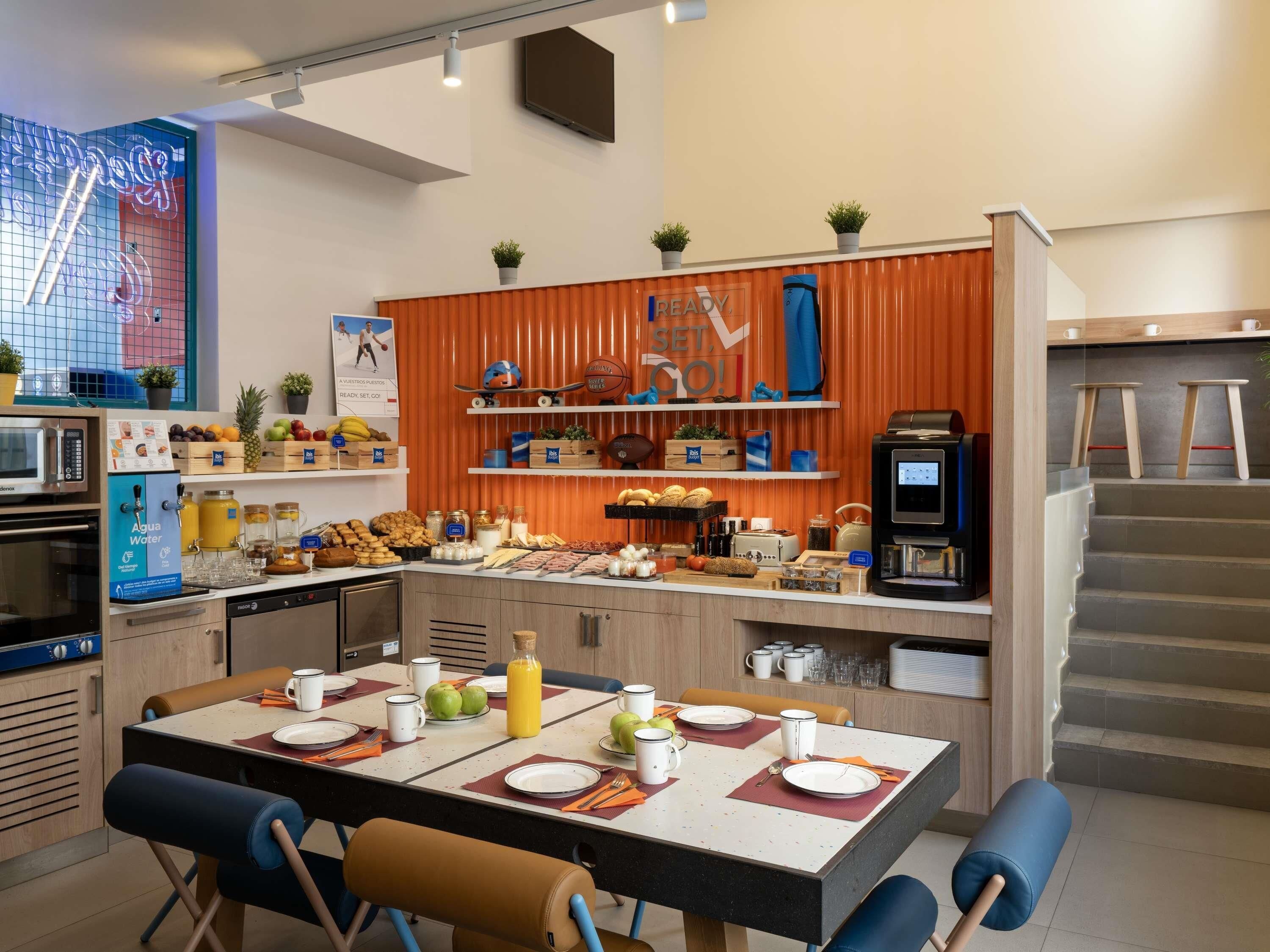 Une cuisine moderne avec un coin repas, équipée d’appareils électroménagers, d’une machine à café et d’une variété de produits alimentaires rangés sur des étagères.