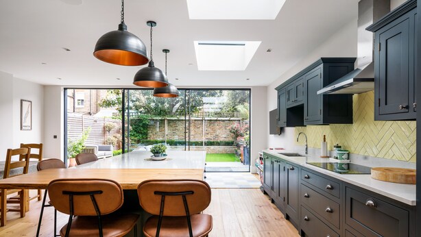 A modern kitchen with dark cabinets, a wooden dining table, and two chairs.