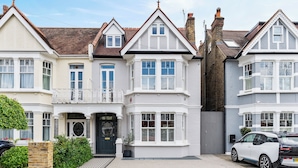 A row of white terraced houses with bay windows and a black car parked in front.
