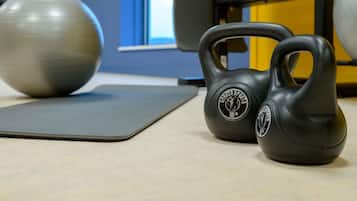 Un gimnasio con equipo de ejercicio, incluyendo pesas rusas y una colchoneta.