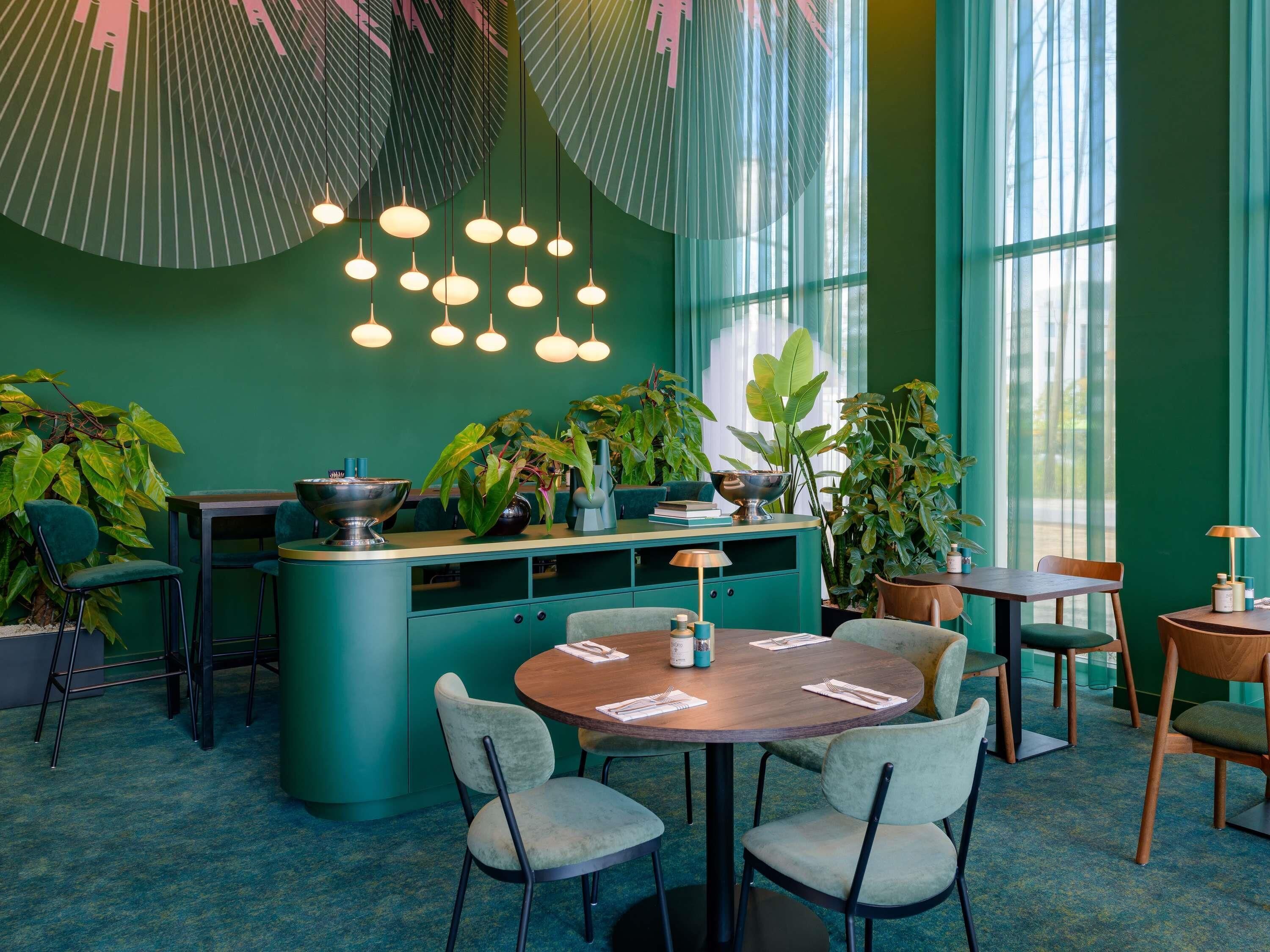 Un intérieur à dominante verte, avec un îlot central, des tables rondes et des chaises.
