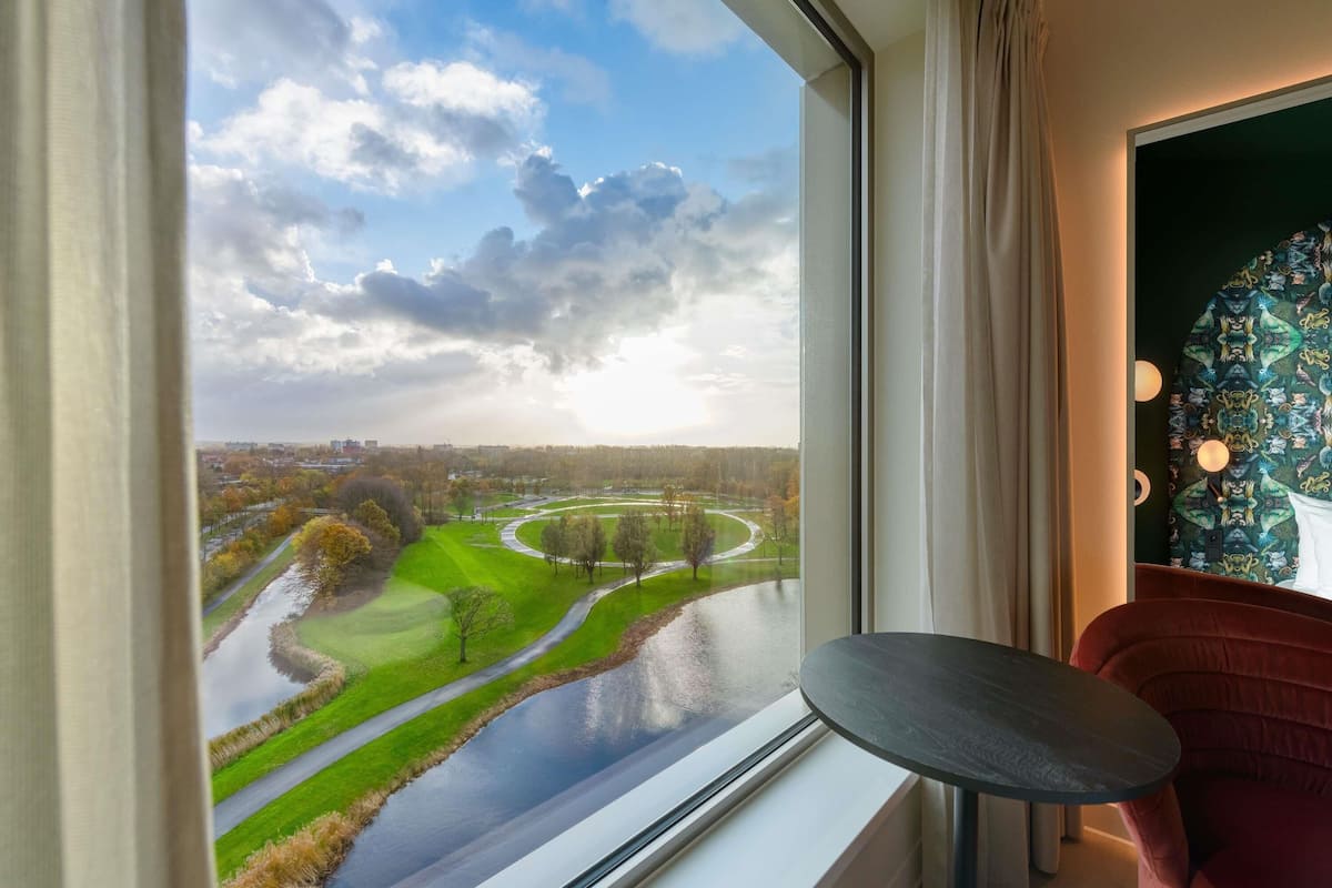 A room with a large window offering a view of a golf course and a river.