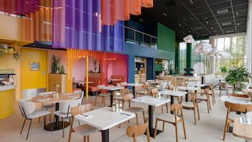 Un restaurante moderno con varias zonas de comedor, incluidas mesas y cabinas, además de una barra.