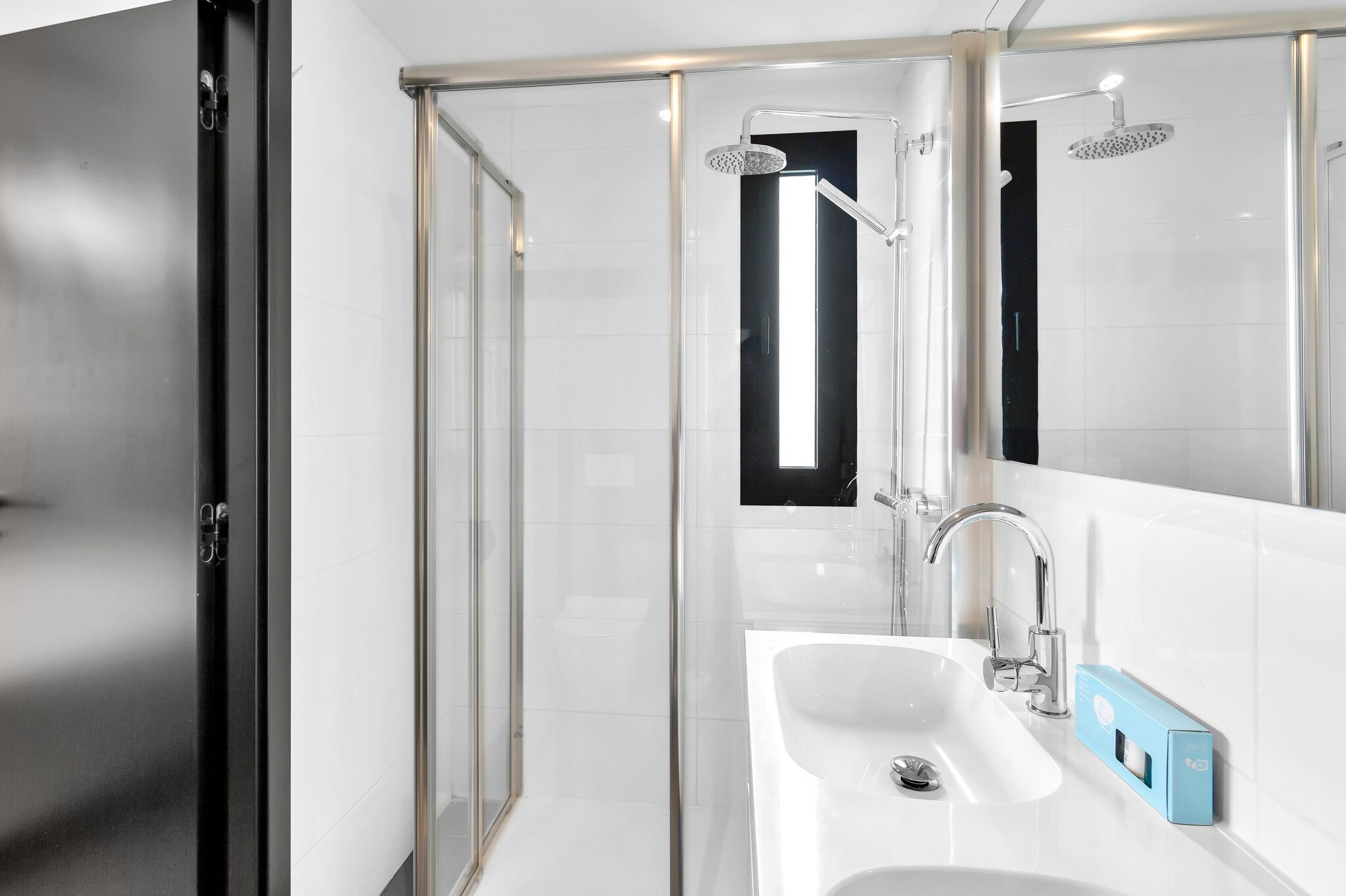 Ein modernes Badezimmer mit Duschkabine aus Glas, einem weißen Waschbecken und einem Spiegel.