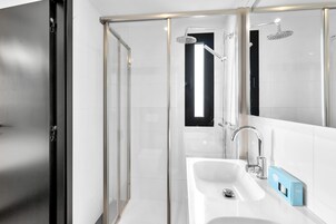 A modern bathroom with a glass shower enclosure, a white sink, and a mirror.
