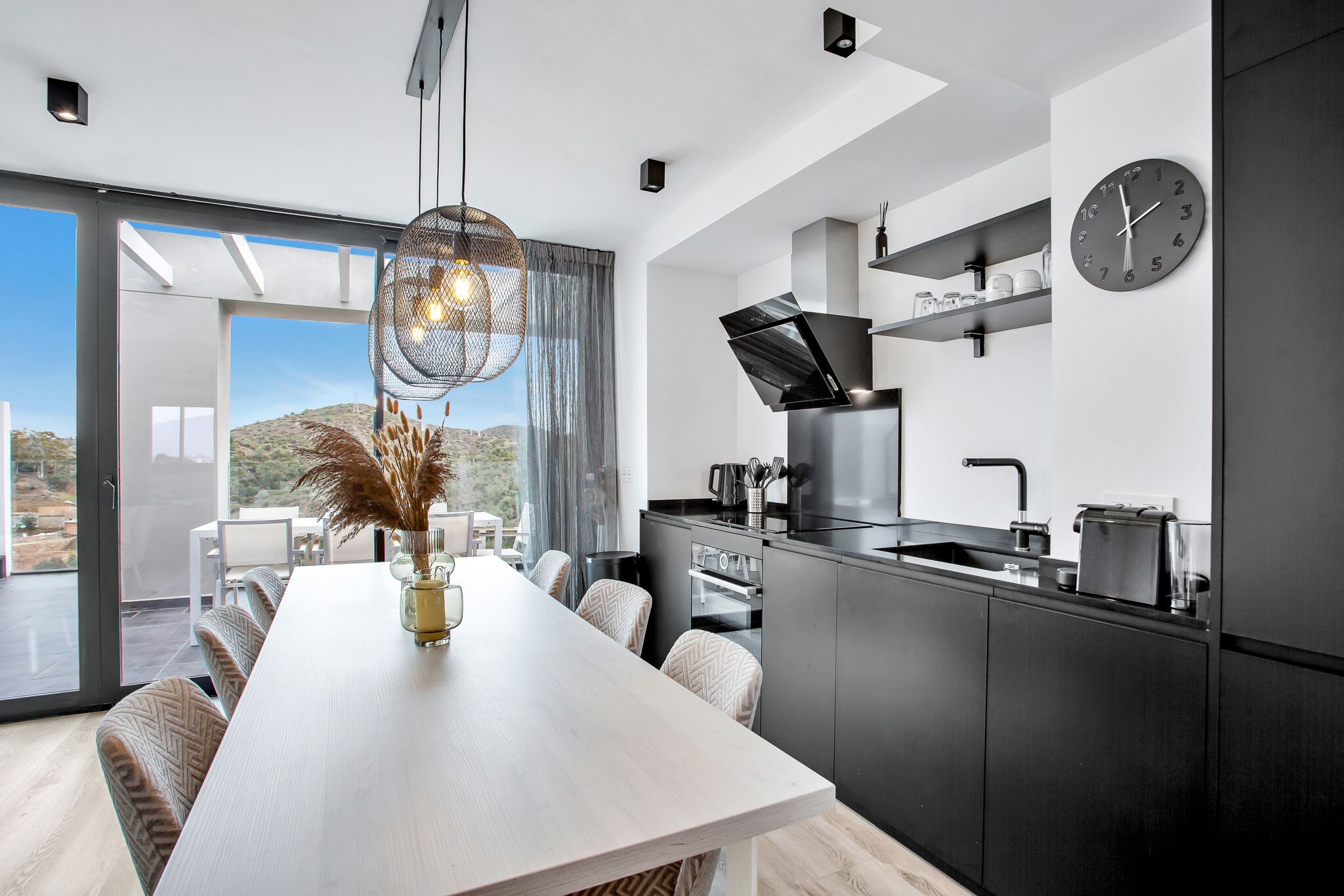 A modern kitchen with a dining area, large windows, and a view of the desert.