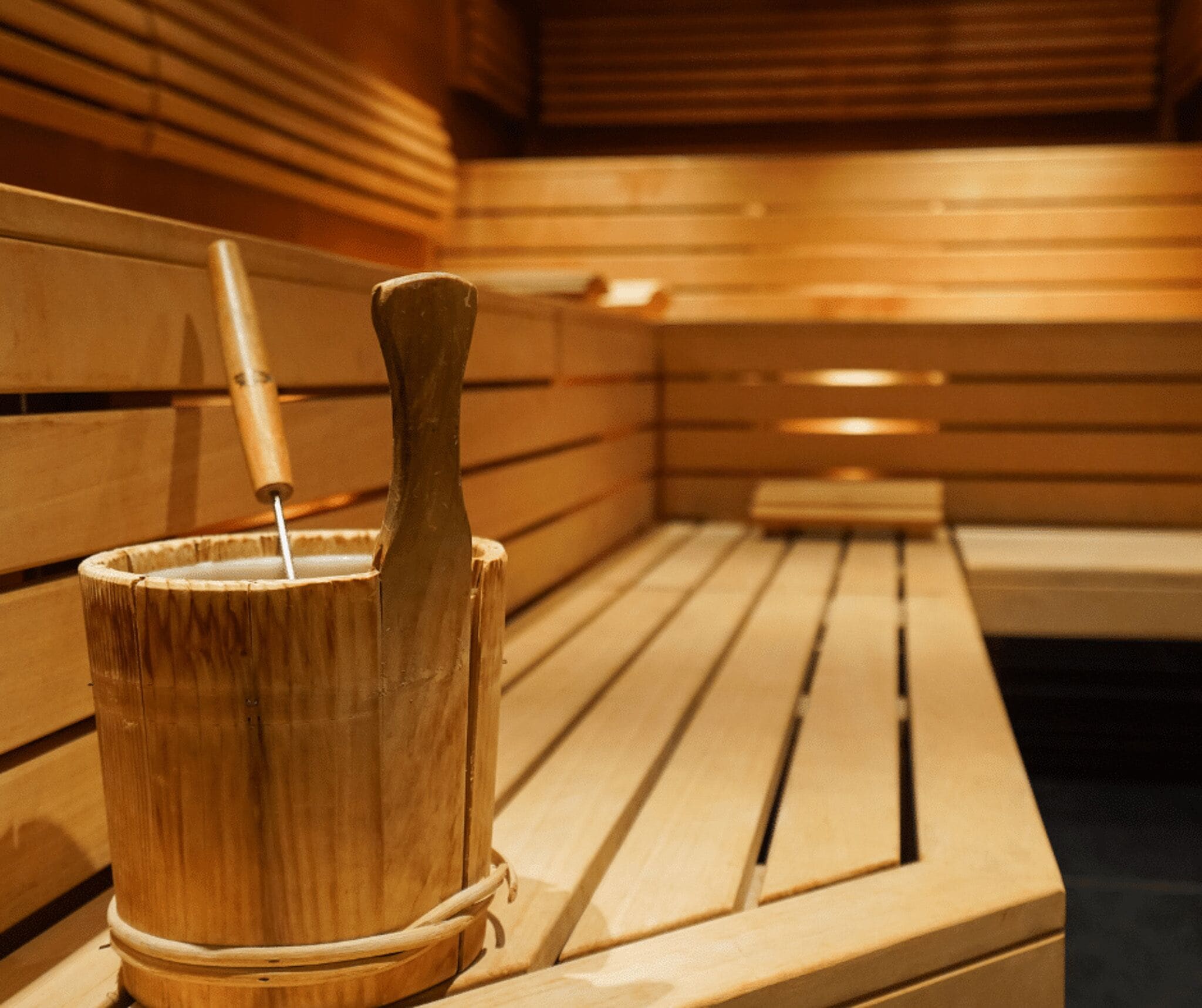 A wooden sauna bench with a wooden bucket and a wooden mallet.