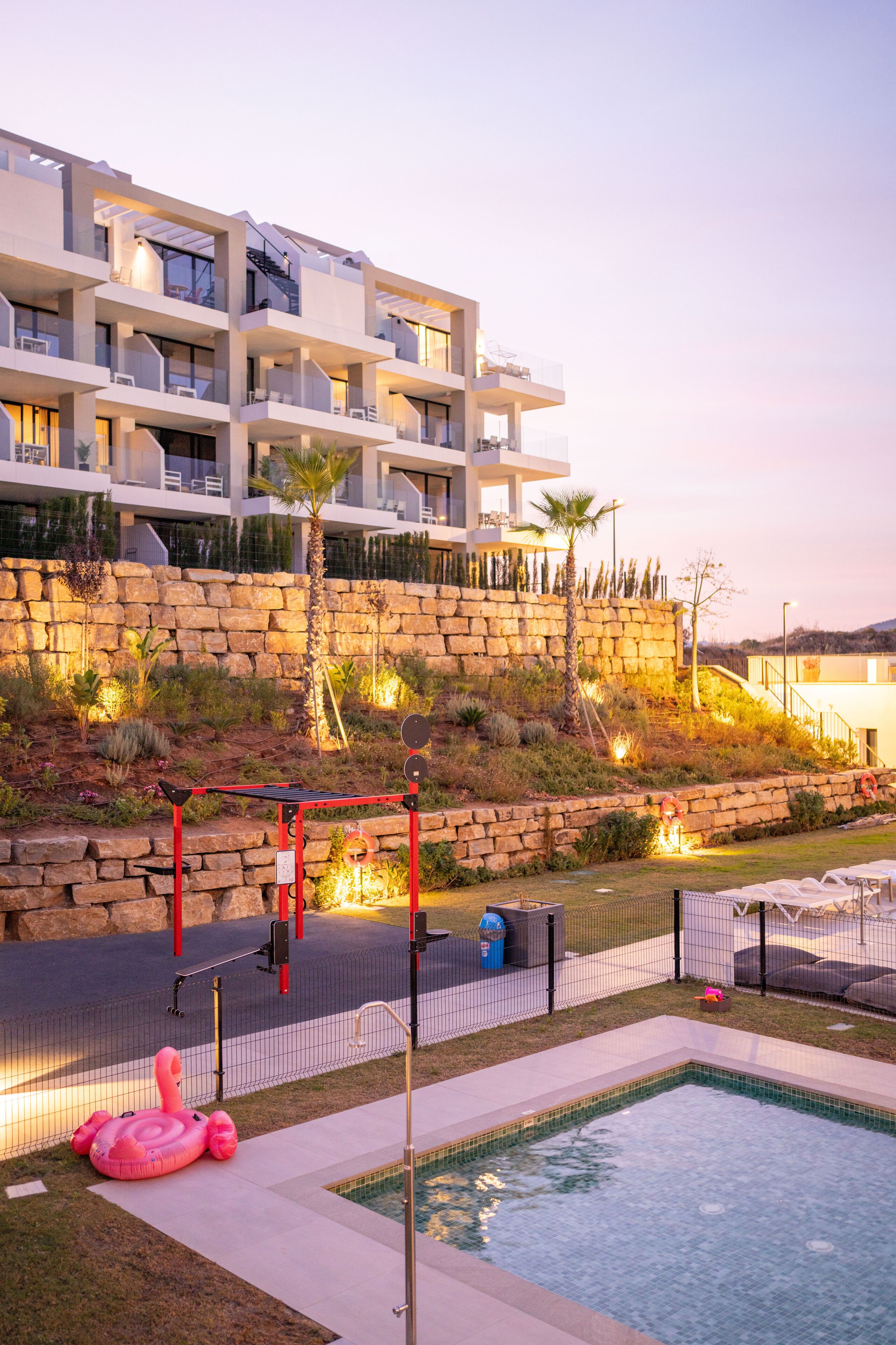 Un hotel moderno con piscina, asientos al aire libre y un jardín ajardinado.