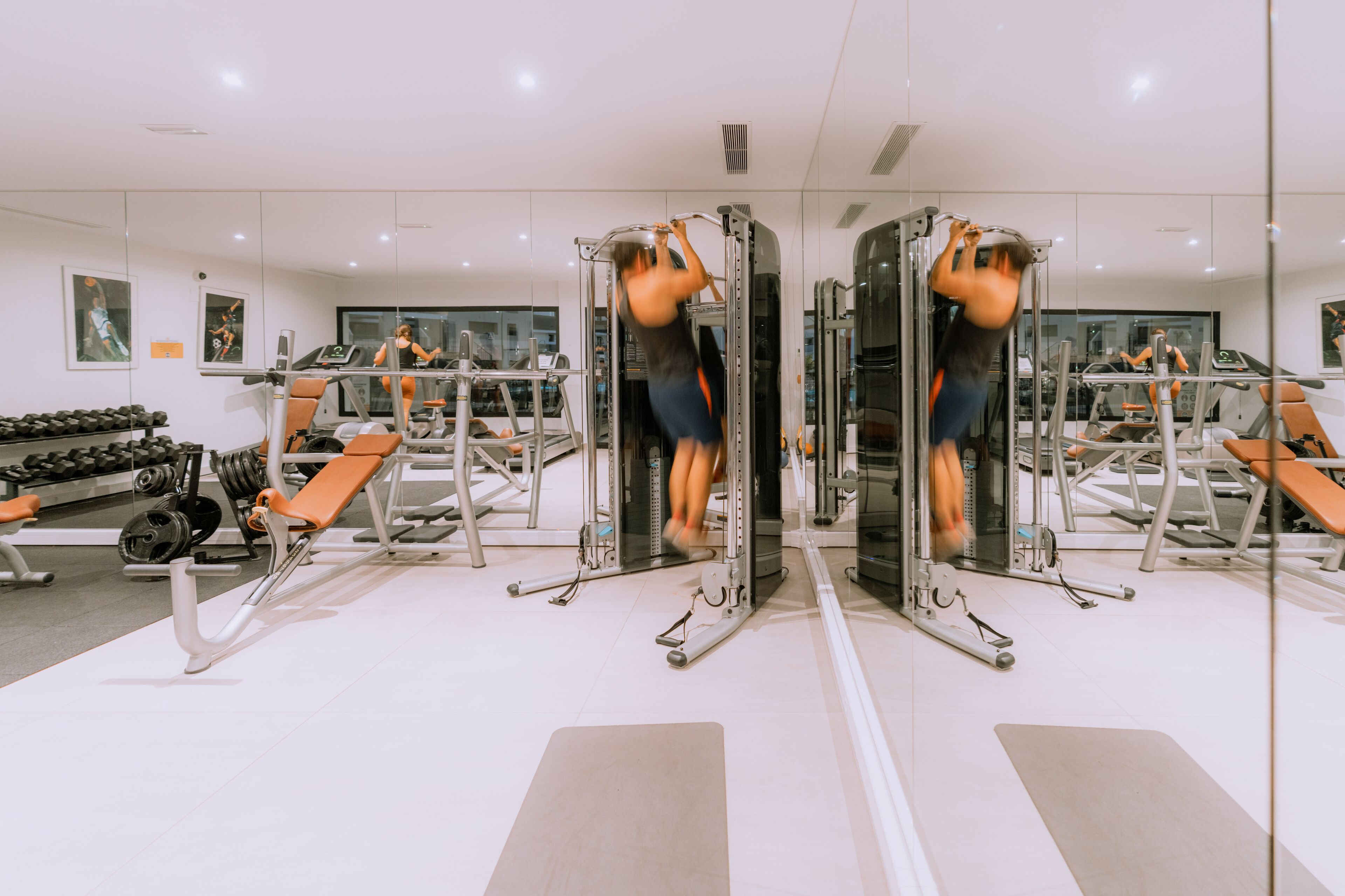 Una palestra con pareti a specchio, attrezzature per l'allenamento e rastrelliere per pesi.