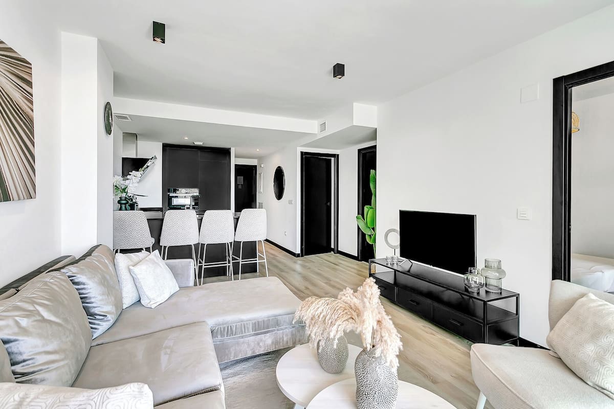 A modern living room with a sofa, chairs, a coffee table, and a TV.