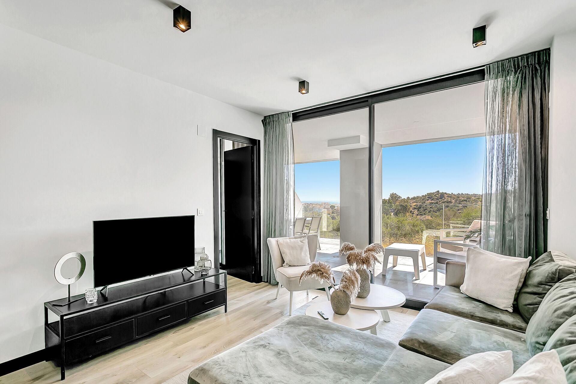 A modern living room with a flat-screen TV, a coffee table, and a sofa.