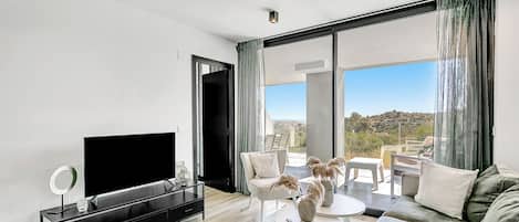 A modern living room with a flat-screen TV, a coffee table, and a sofa.