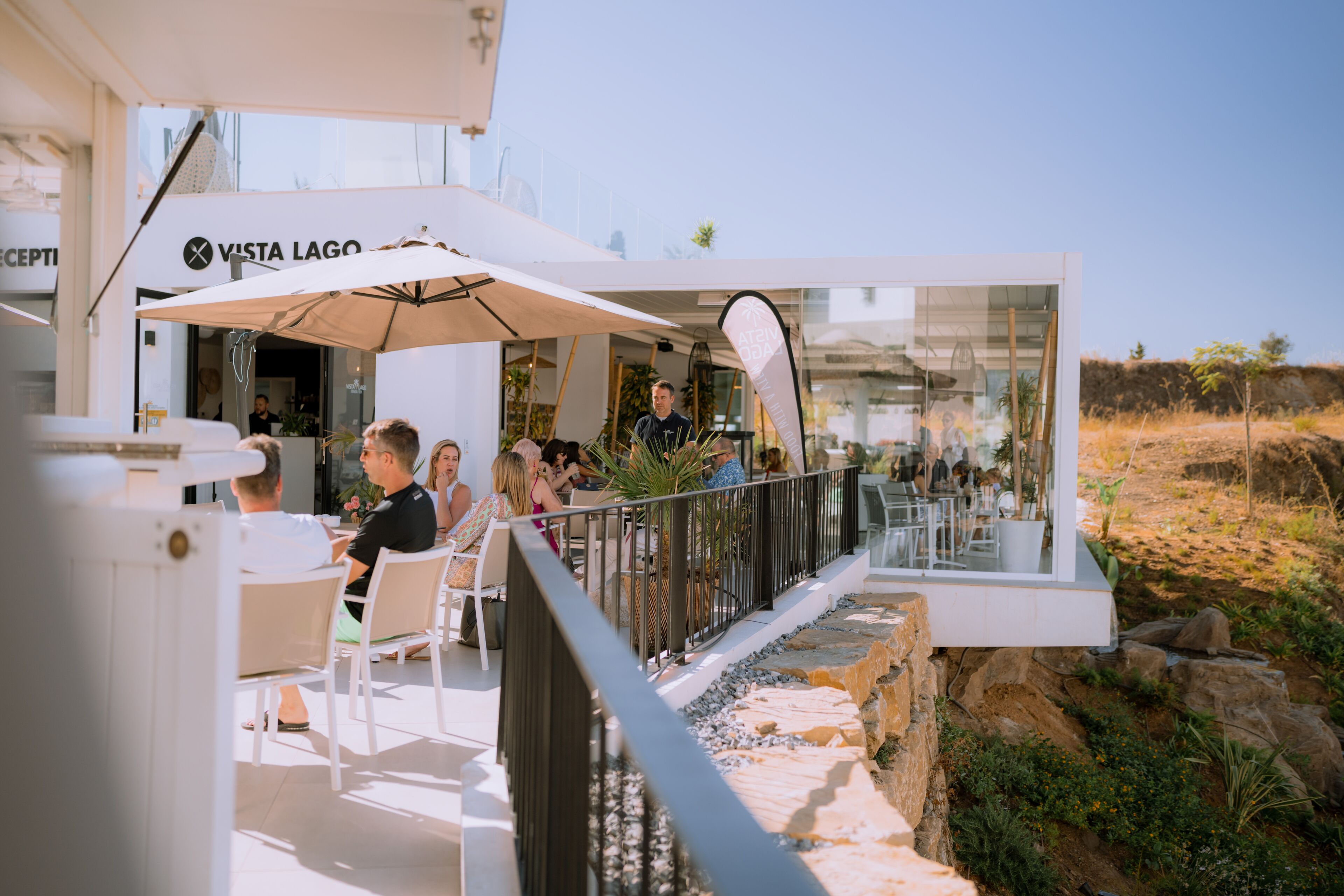 An outdoor seating area with tables and umbrellas, overlooking a rocky landscape.