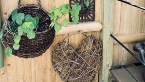 A wooden fence with a decorative sunburst pattern, a wicker basket with plants, and a small wall-mounted decoration. - 🌾Welcoming Tiny Home! Downtown & Beachy☀️ (Guilford)