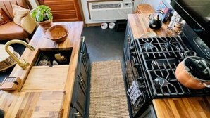 A compact kitchen with wooden countertops, a gas stove, and a built-in oven. - 🌾Welcoming Tiny Home! Downtown & Beachy☀️ (Guilford)