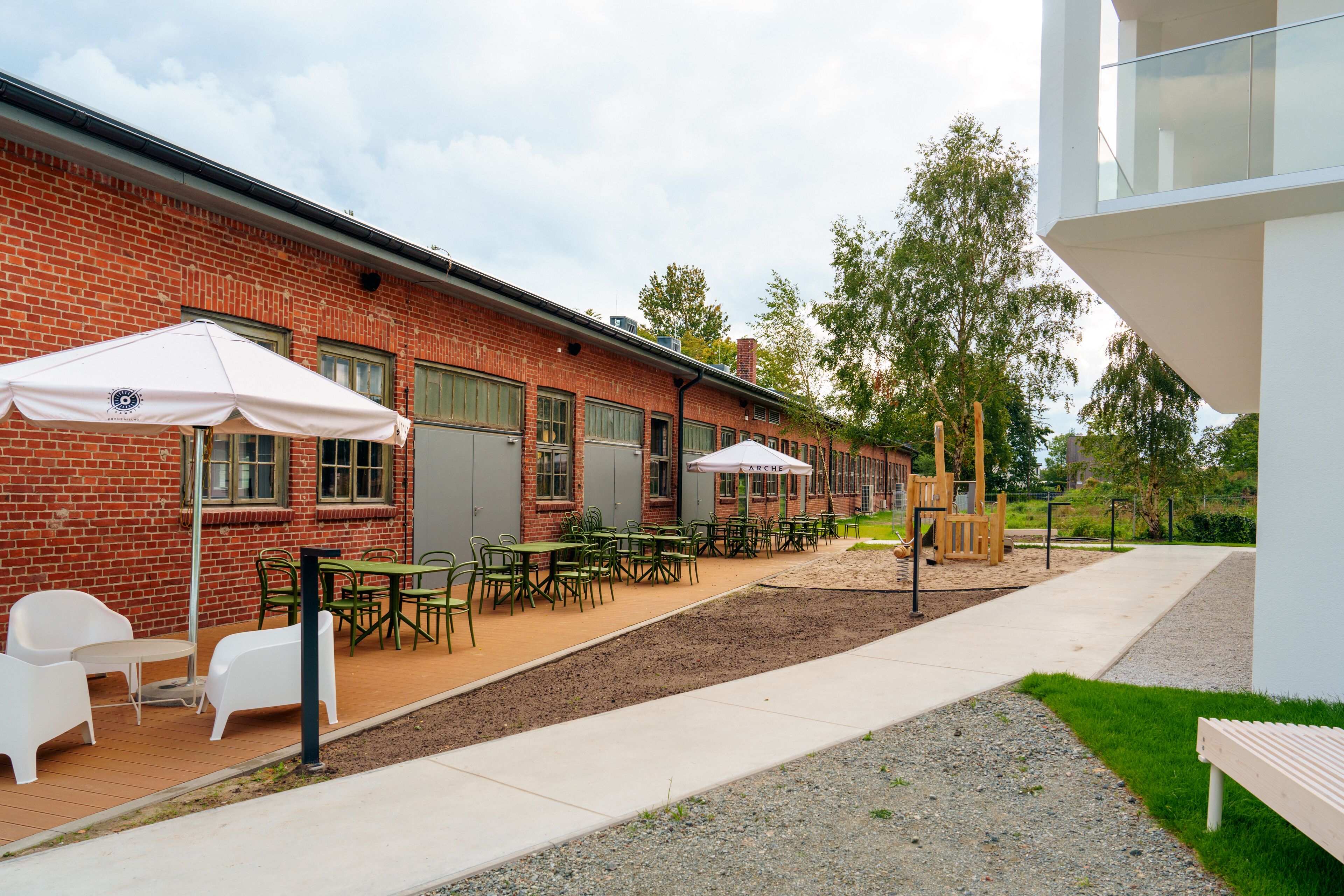 A courtyard with outdoor seating, a brick building, and a modern structure.