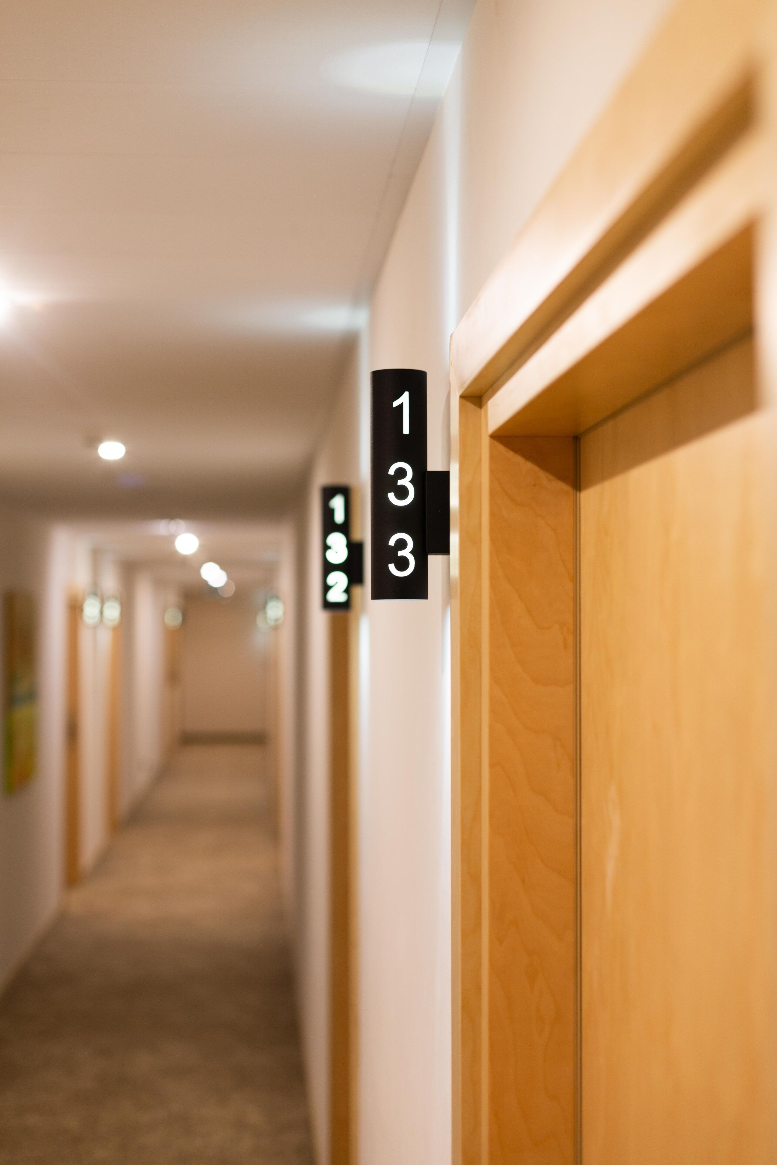 A hotel hallway with wooden doors and numbered room signs.