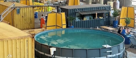 Amplia zona de piscina interior con varias piscinas, rodeada de contenedores marítimos y equipo industrial.
