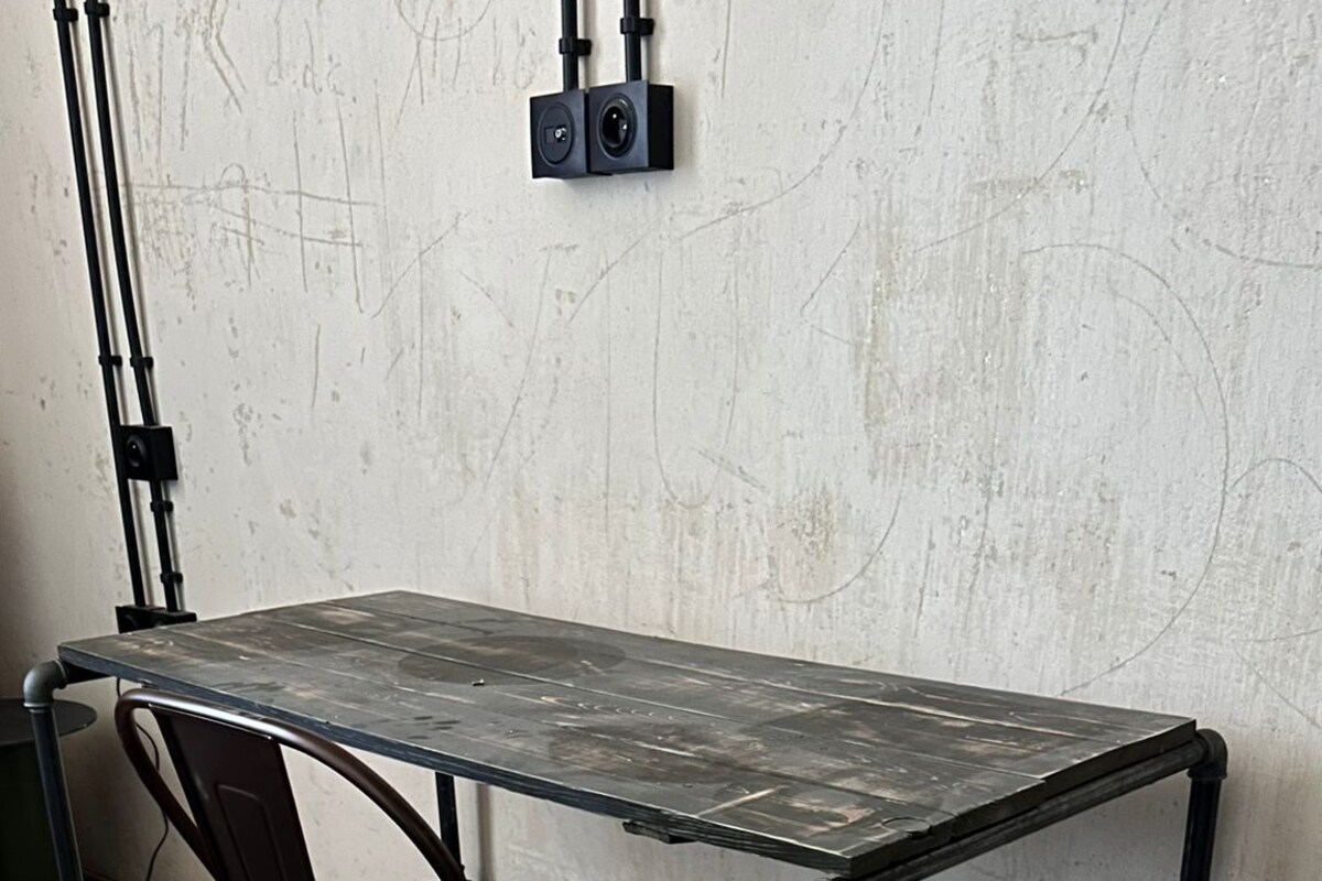Mesa de estructura metálica con una silla en una habitación con piso de concreto y pared lisa.