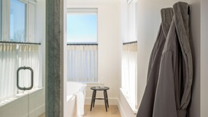A hotel room with a bed, a small table, and a window with curtains. - Longfellow Hotel (Portland)