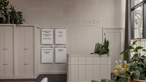 A wellness spa interior with a reception desk, potted plants, and wellness-related posters. - Longfellow Hotel (Portland)