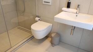 A modern bathroom with a toilet, sink, and shower. - 1 Doppelbett Zimmer 21 (München)