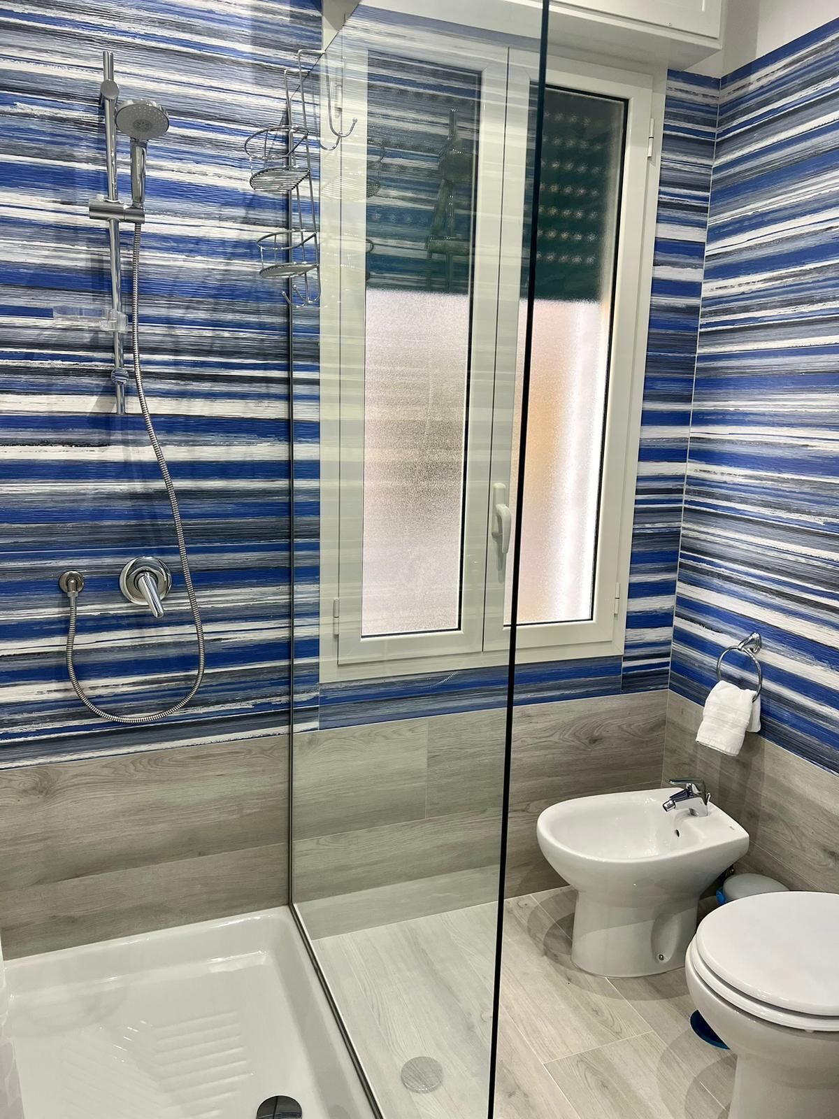 Uma casa de banho moderna com chuveiro em cabine de vidro, um bidé e uma sanita.