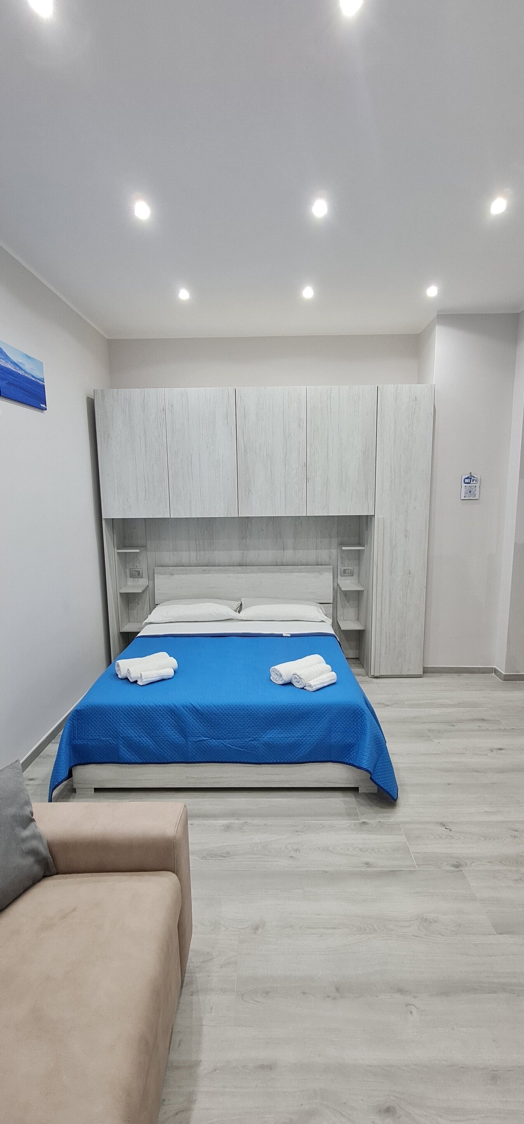 A modern bedroom with a bed, a sofa, and built-in wardrobes.