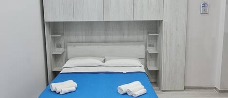 A modern bedroom with a bed, a sofa, and built-in wardrobes.