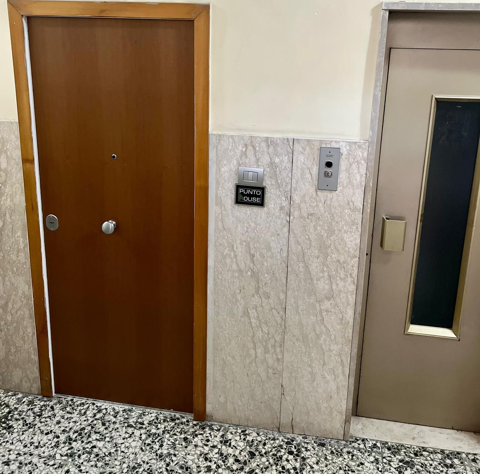 Uma porta de madeira com puxador de metal e uma placa acima que diz 'PUNTO HOUSE'.