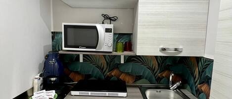 A compact kitchen with a microwave, coffee maker, and a sink.