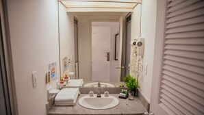 A bathroom with a sink, mirror, towel rack, and a hairdryer on the wall. - Hotel Estación by Destino Pacifico (Buenaventura)