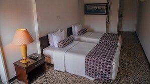 A hotel room with two beds, a nightstand, a lamp, and a painting on the wall. - Hotel Estación by Destino Pacifico (Buenaventura)