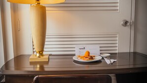 A hotel room with a wooden desk, a lamp, a chair, a plate with food, and a door with a lock. - Hotel Estación by Destino Pacifico (Buenaventura)