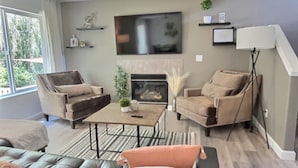 Un salon moderne avec une cheminée, deux fauteuils, un canapé et une table basse.