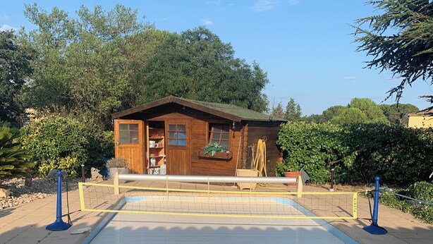 A pool area with a wooden cabin in the background.