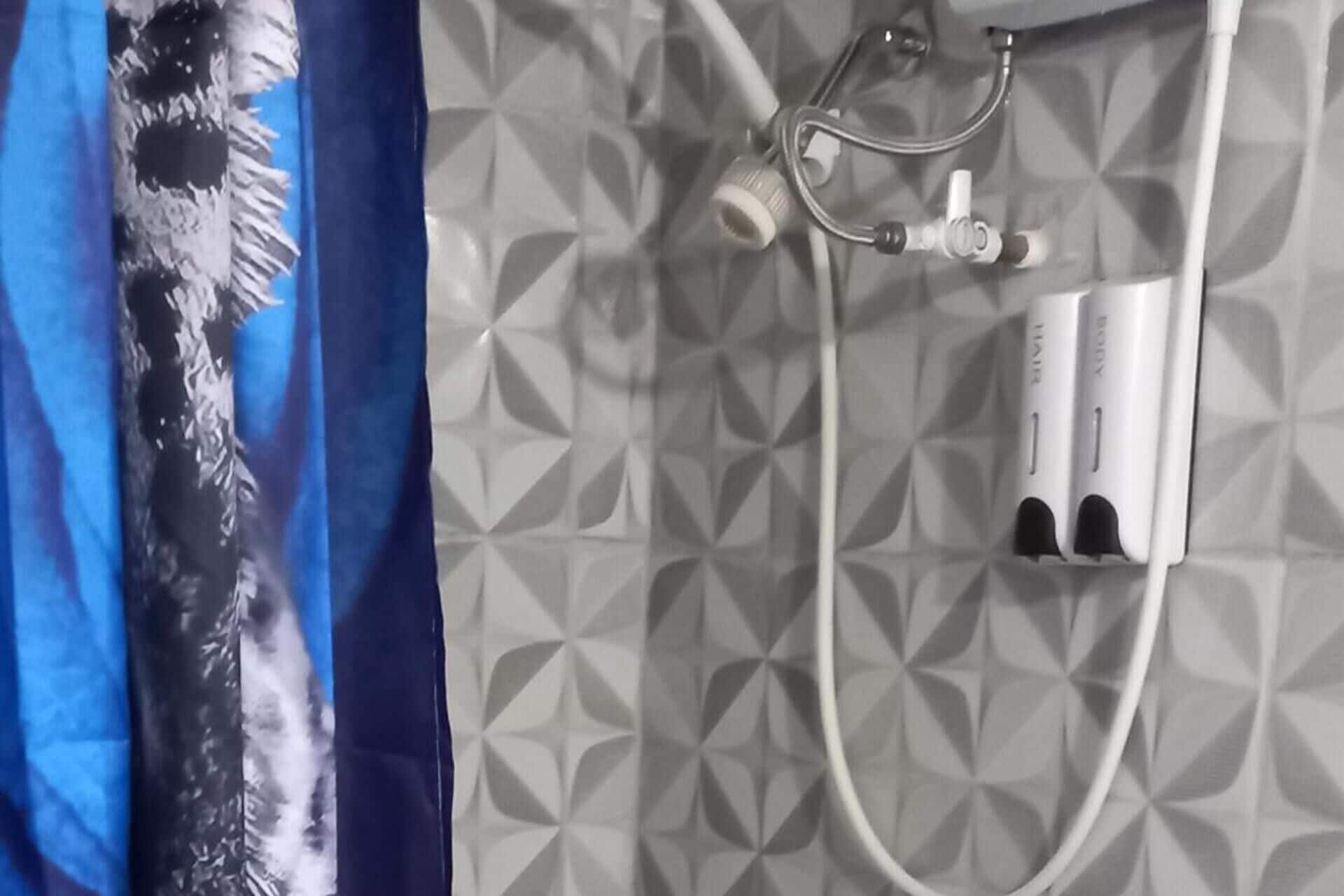 Une salle de bain avec une douche, un porte-serviettes et un mur décoré d’un motif.