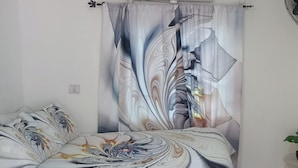 A bedroom with a bed, a curtain with a marbled design, and a small table with a plant. - House - Sleeps 6 - Patio - Parking (Port Morant)