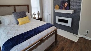 Une chambre à coucher avec un lit, une porte blanche, une cheminée et un tableau au mur.