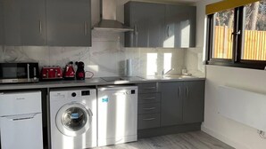 Una cocina moderna con armarios grises, una lavadora de acero inoxidable, un microondas y un tostador.