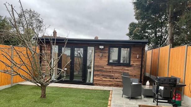 Una casa moderna con un patio, un pequeño jardín y una zona de barbacoa.