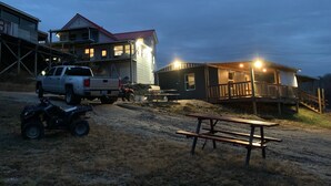 Een woonhuis met twee verdiepingen, met een rood dak, een overdekte veranda en een picknicktafel ervoor.