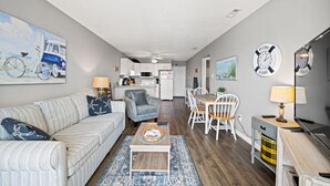 A modern living room with a sofa, coffee table, and dining area.