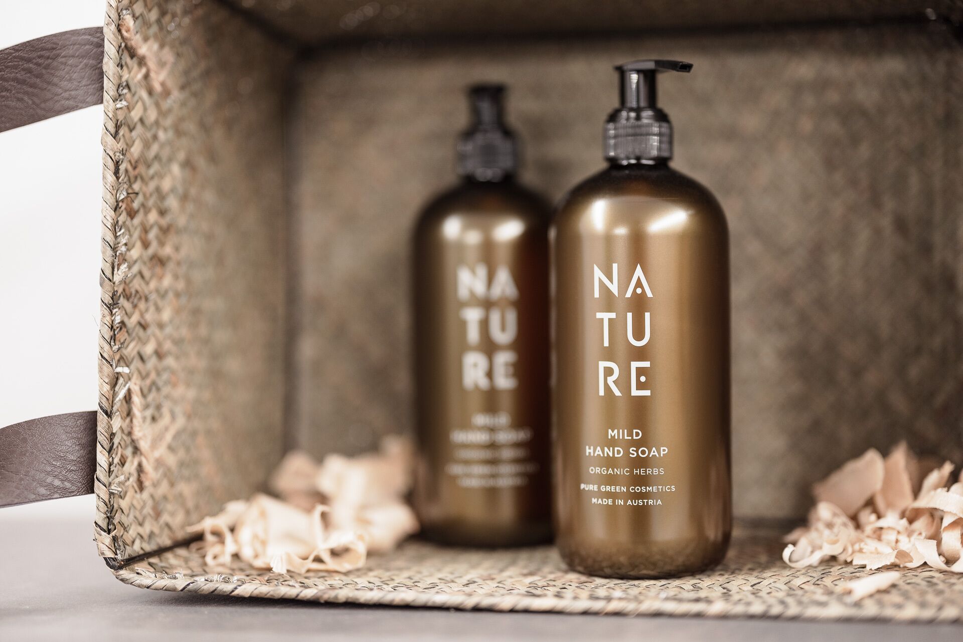 Two bottles of Nature hand soap in a woven basket.