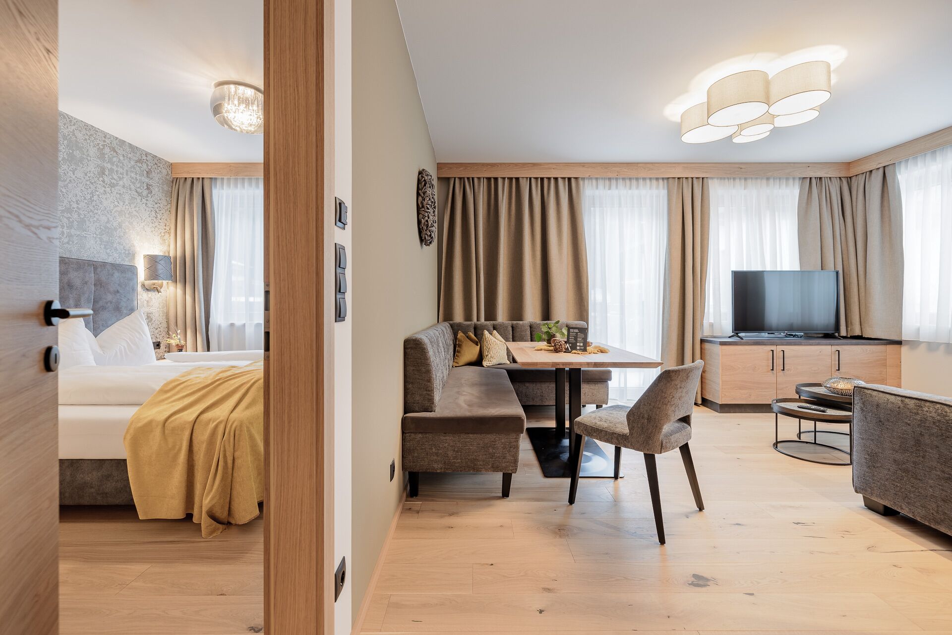 Una habitación de hotel moderna con cama, sofá, mesa de comedor y televisor.