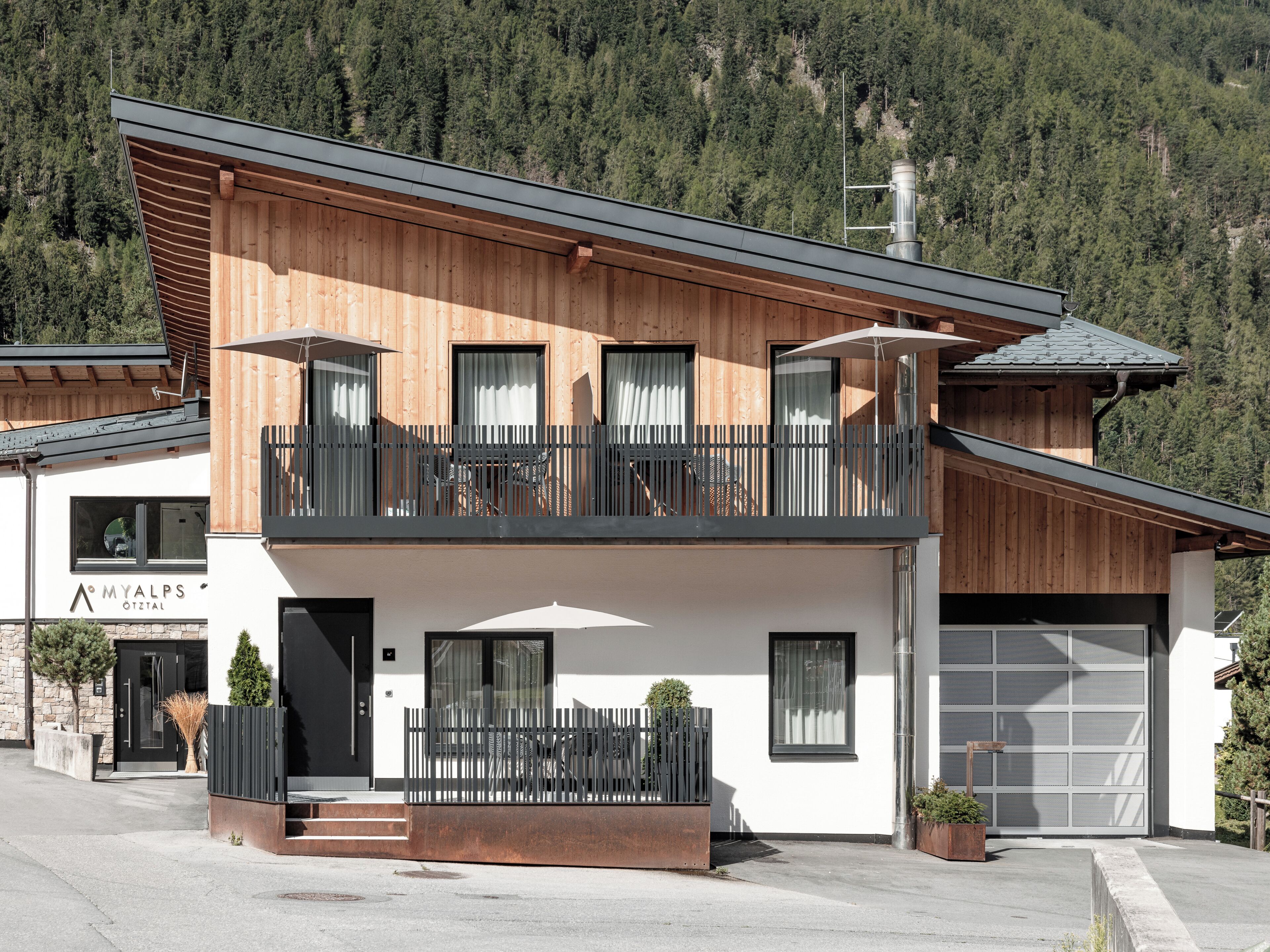 A modern two-story building with a balcony, a garage, and a sign that reads 'MYALPS OTZTAL'.