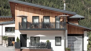 A modern two-story building with a balcony, a garage, and a sign that reads 'MYALPS OTZTAL'.