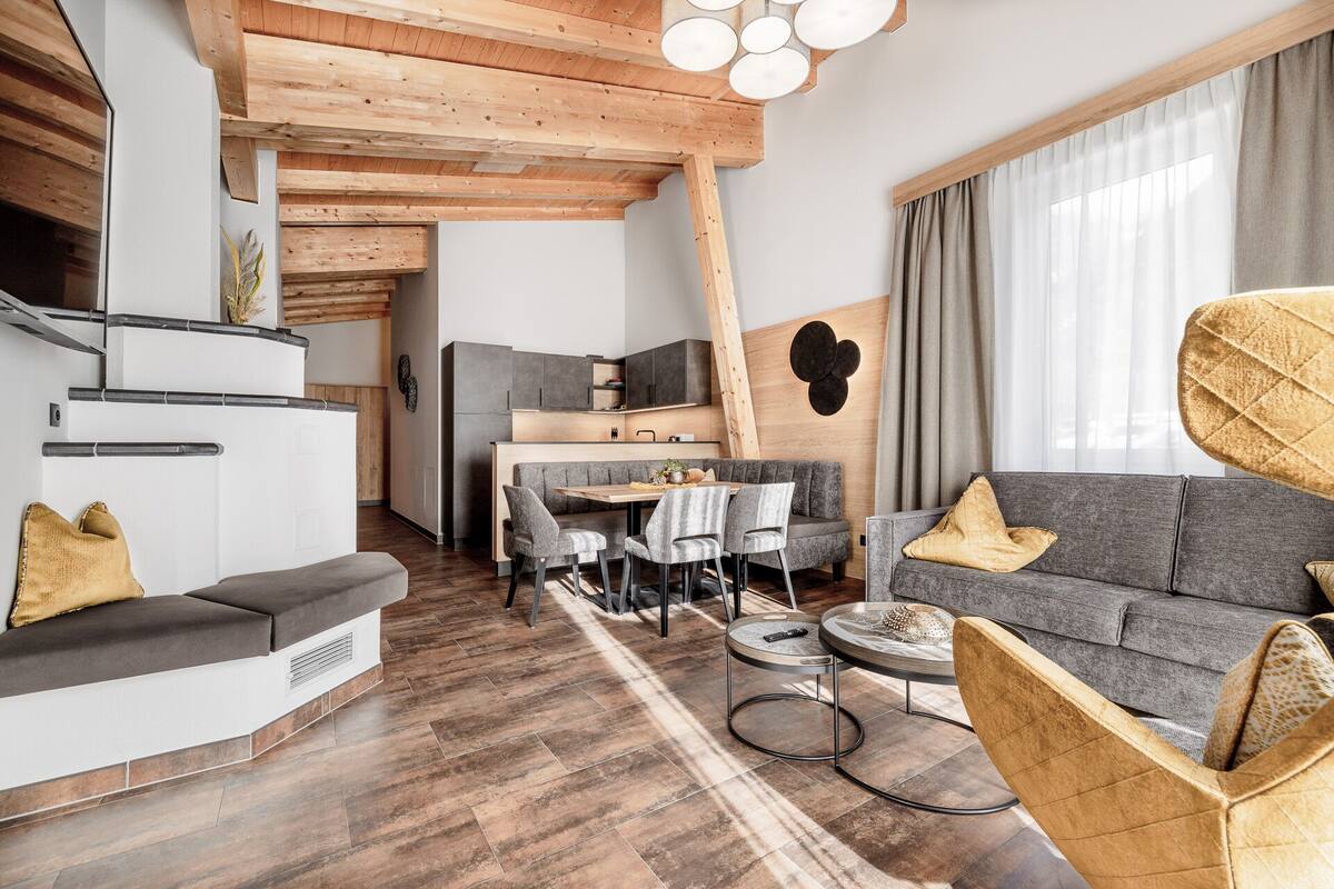 Ein modernes Wohnzimmer mit einem grauen Sofa, einem Essbereich und einer Küche im Hintergrund.