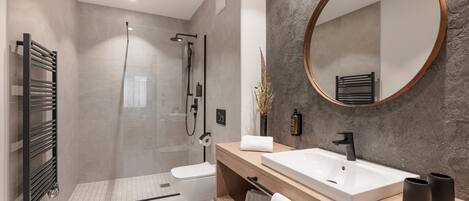 Un baño moderno con cabina de ducha, un espejo grande y un tocador de madera con lavabo blanco.
