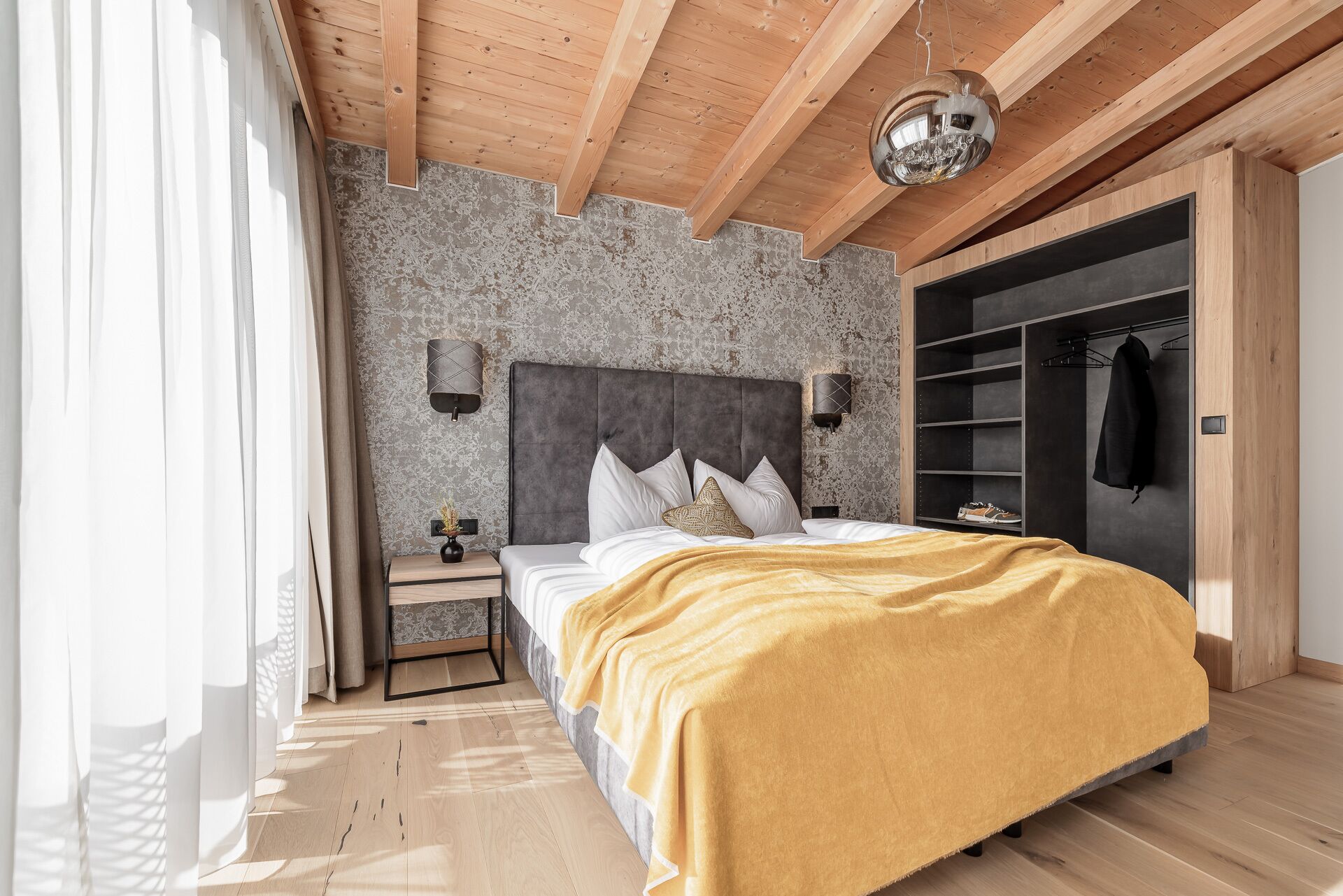 A bedroom with a bed, bedside tables, a wardrobe, and a ceiling light.